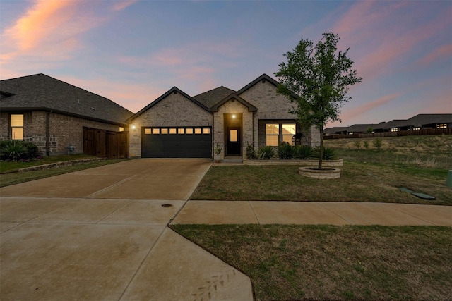 view of front of property featuring stone siding, an attached garage, a front yard, brick siding, and driveway