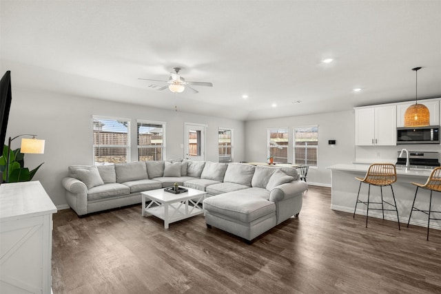 living area with dark wood finished floors, baseboards, ceiling fan, and a healthy amount of sunlight