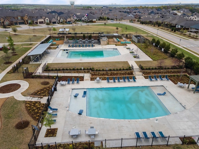 view of swimming pool featuring a patio, fence, and a residential view