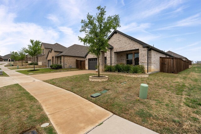 view of front facade featuring driveway, a front yard, fence, brick siding, and a garage