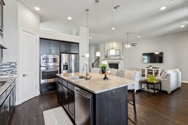 4600 Autumn Sage Dr, Prosper, TX 75078 - kitchen with appliances with stainless steel finishes, a sink, open floor plan, a fireplace, and a kitchen breakfast bar