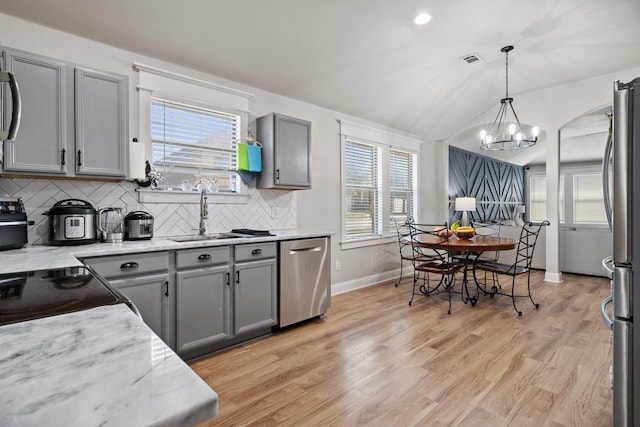 3968 Hunter Peak Rd, Fort Worth, TX 76262 - kitchen with appliances with stainless steel finishes, gray cabinetry, decorative backsplash, vaulted ceiling, and a chandelier
