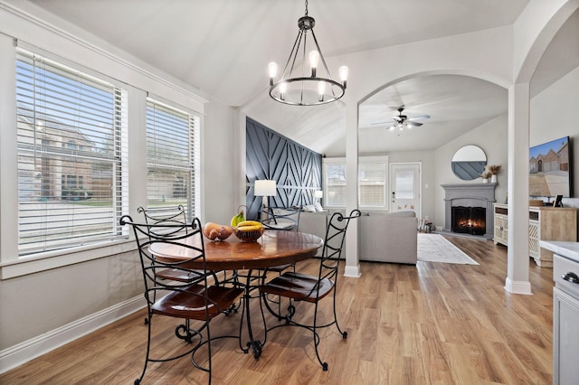 3968 Hunter Peak Rd, Fort Worth, TX 76262 - dining room featuring a ceiling fan, light wood finished floors, a warm lit fireplace, a chandelier, and arched walkways