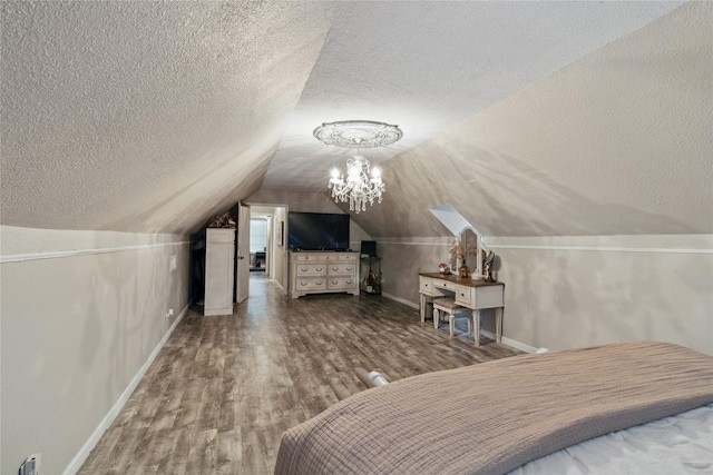 bedroom featuring a textured ceiling, wood finished floors, baseboards, and lofted ceiling
