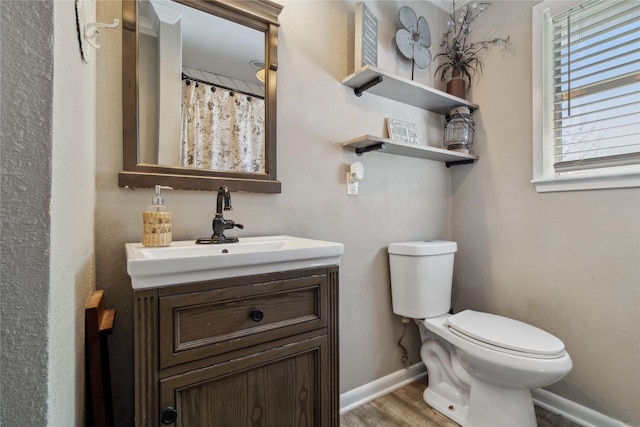 bathroom featuring vanity, baseboards, toilet, and wood finished floors