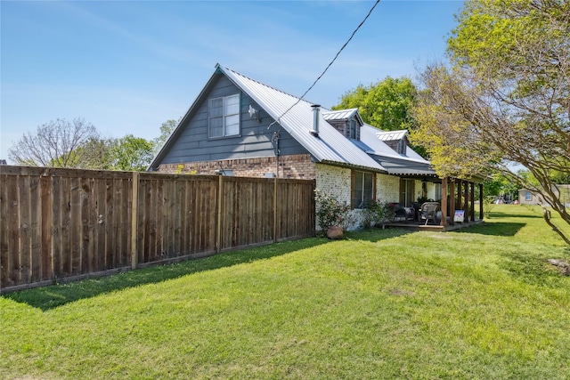 view of home's exterior with a yard, metal roof, fence, and brick siding