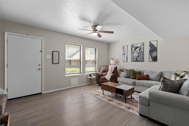 1905 W Morton St Unit 5, Denison, TX 75020 - living room featuring ceiling fan, light wood-style flooring, baseboards, and a textured ceiling