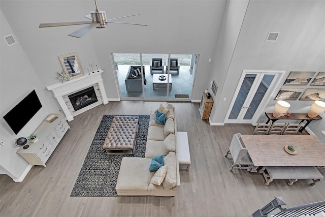 2500 Rosecroft Ct, Celina, TX 75009 - living room featuring a high ceiling, ceiling fan, wood finished floors, baseboards, and a glass covered fireplace
