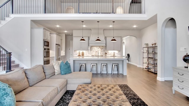 2500 Rosecroft Ct, Celina, TX 75009 - living room with arched walkways, light wood-style floors, stairs, a towering ceiling, and baseboards