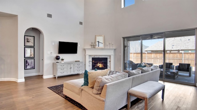 2500 Rosecroft Ct, Celina, TX 75009 - living room featuring a towering ceiling, arched walkways, wood finished floors, baseboards, and a stone fireplace