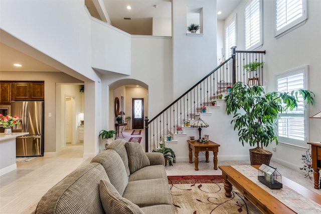 living area featuring arched walkways, plenty of natural light, and a high ceiling