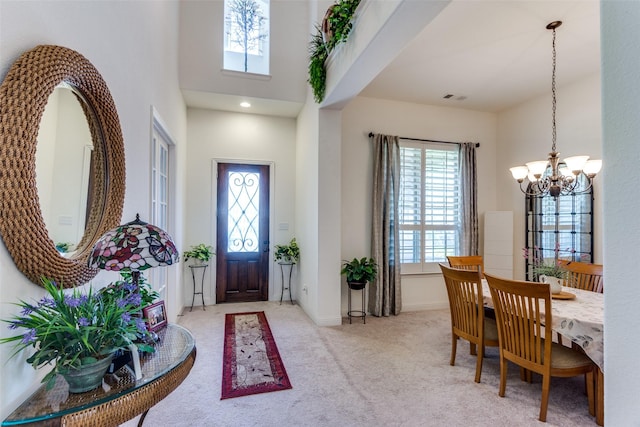 entrance foyer featuring a chandelier, a healthy amount of sunlight, carpet flooring, and baseboards