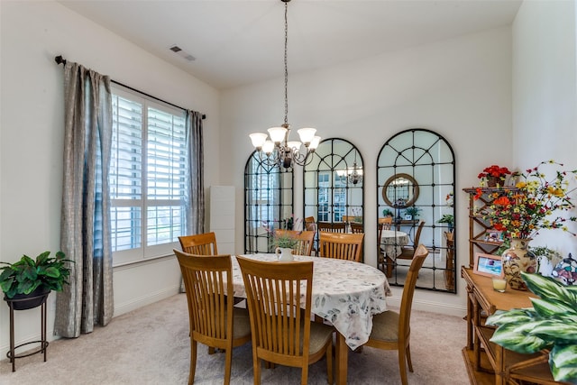 dining area with light colored carpet, a wealth of natural light, a chandelier, and baseboards