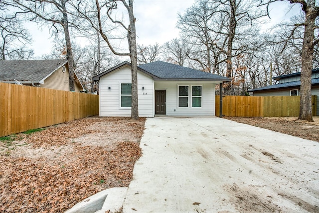 view of front of home featuring roof with shingles, driveway, and fence