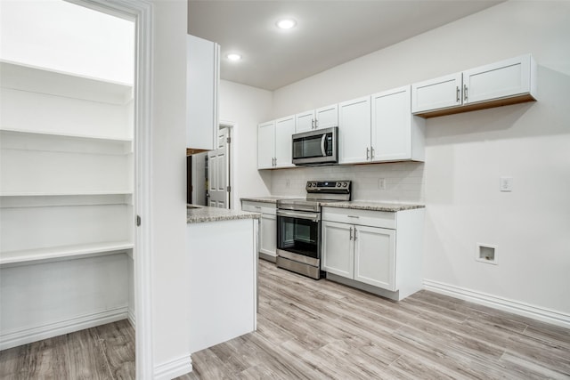 kitchen featuring white cabinetry, stainless steel appliances, tasteful backsplash, and light wood-type flooring