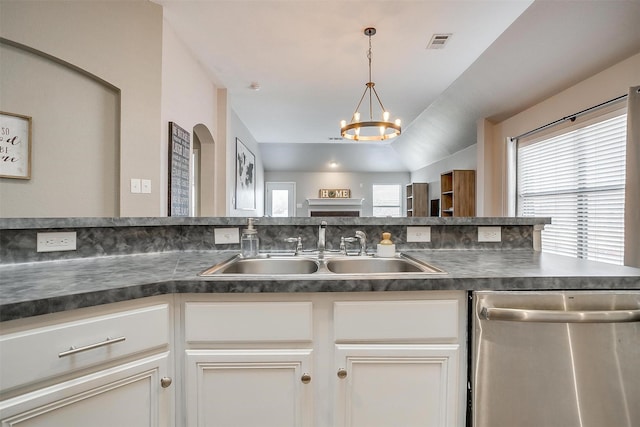 kitchen with a chandelier, stainless steel dishwasher, a sink, dark countertops, and visible vents