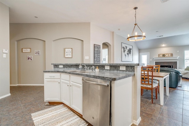 kitchen featuring dishwasher, open floor plan, a sink, and dark countertops