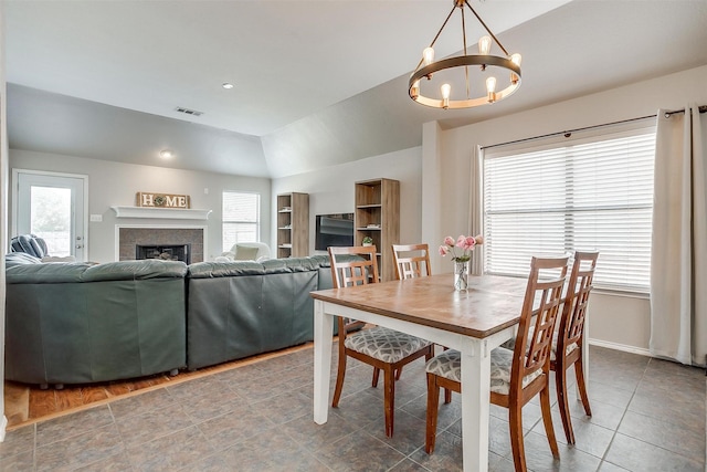 dining space featuring lofted ceiling, baseboards, a chandelier, visible vents, and a fireplace
