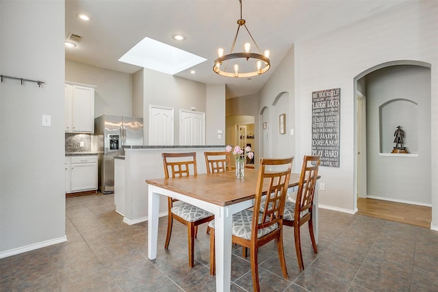 dining room featuring arched walkways, a skylight, a chandelier, and visible vents