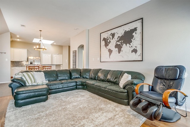 living area featuring visible vents, a notable chandelier, arched walkways, and wood finished floors