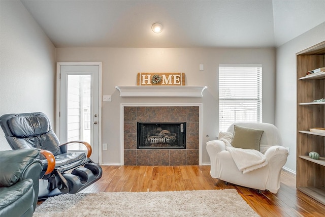 living room with a tile fireplace and wood finished floors