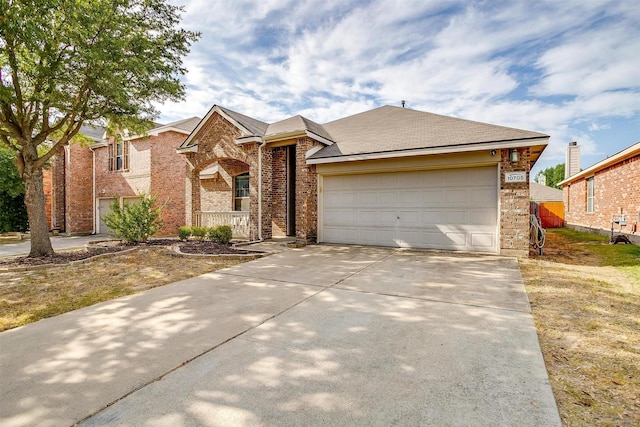 view of front of house with driveway, brick siding, and a garage