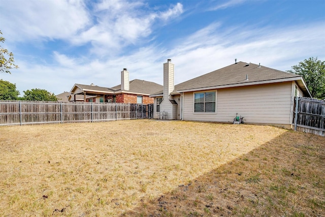 rear view of property with a fenced backyard and a yard