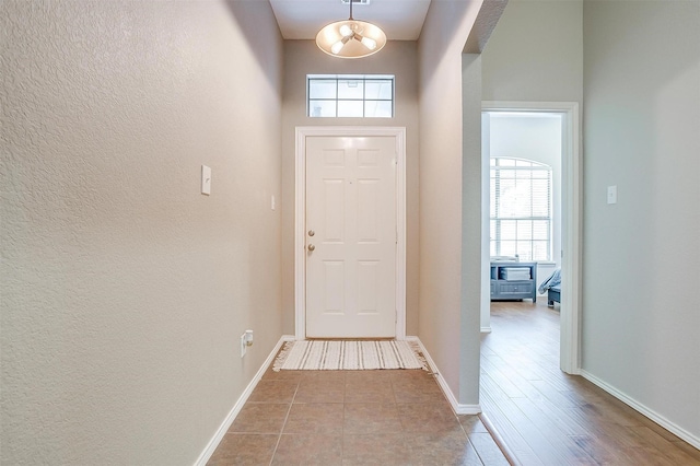 doorway to outside with baseboards, tile patterned floors, and a chandelier