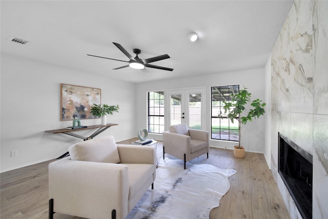 7724 Standish Cir, Plano, TX 75025 - living room featuring french doors, a tiled fireplace, wood finished floors, and a ceiling fan