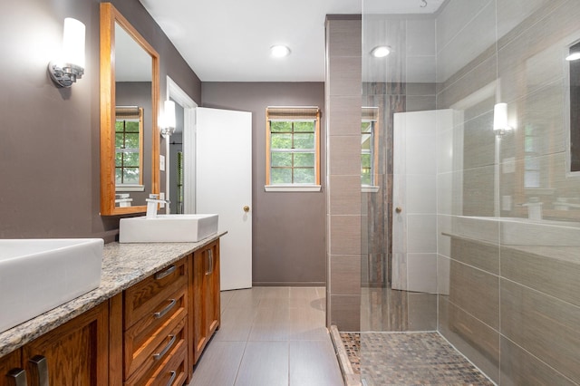 2306 Ravenwood Dr, Grand Prairie, TX 75050 - bathroom featuring tiled shower, double vanity, tile patterned floors, and baseboards
