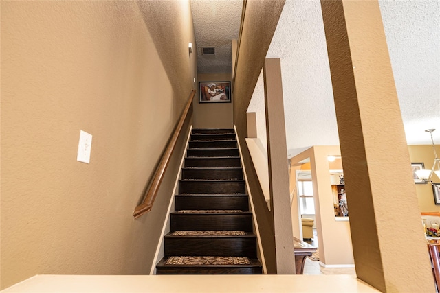 stairway featuring a textured ceiling and visible vents