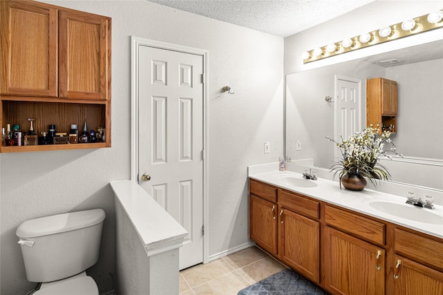 bathroom featuring toilet, tile patterned flooring, a sink, and double vanity