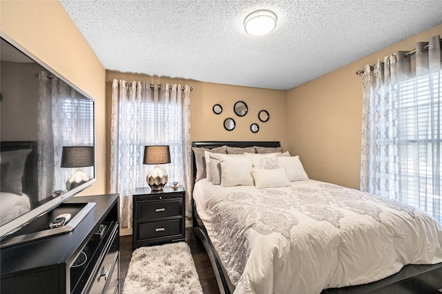 bedroom with a textured ceiling and dark wood-style flooring