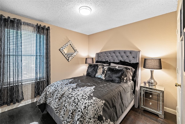 bedroom with wood finished floors, a textured ceiling, and baseboards