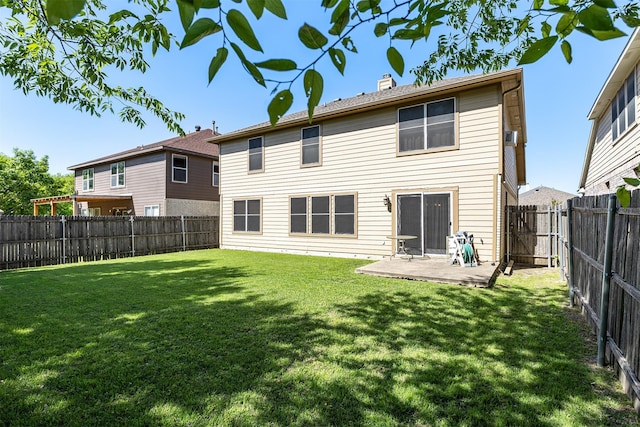 back of house featuring a fenced backyard, a chimney, a patio, and a lawn