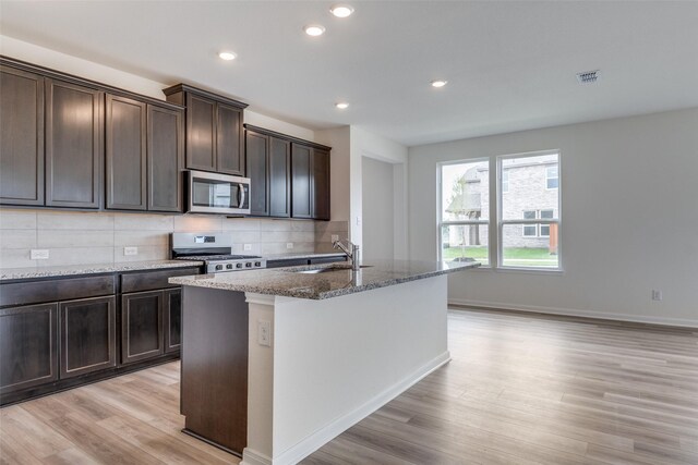 3836 Parsons St, Crandall, TX 75114 - kitchen with stone countertops, light wood-type flooring, tasteful backsplash, a sink, and stainless steel appliances