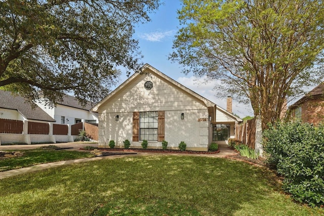 view of front facade with a chimney, fence, a front lawn, and brick siding