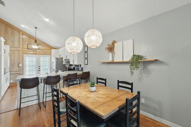 dining room with visible vents, baseboards, vaulted ceiling, and wood finished floors
