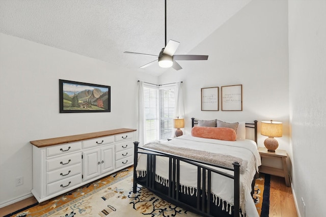 bedroom featuring baseboards, a ceiling fan, a textured ceiling, vaulted ceiling, and light wood-style flooring