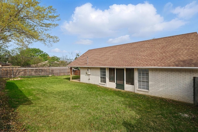 back of house featuring a yard, a shingled roof, a fenced backyard, and brick siding