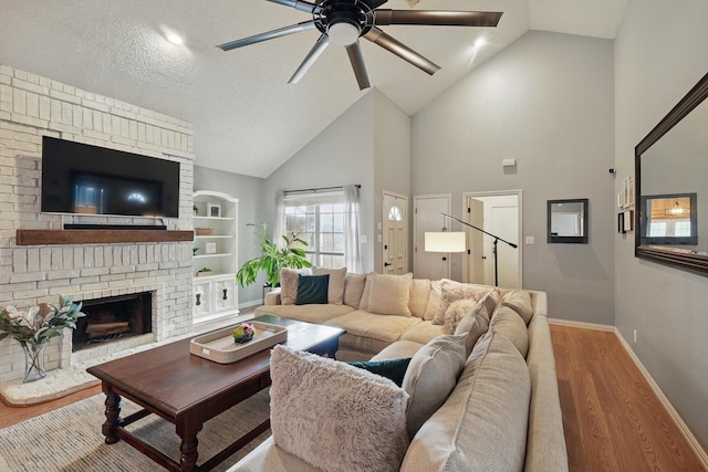 living room with baseboards, a fireplace, ceiling fan, built in shelves, and wood finished floors