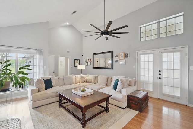 living area with visible vents, a ceiling fan, light wood-style floors, french doors, and high vaulted ceiling