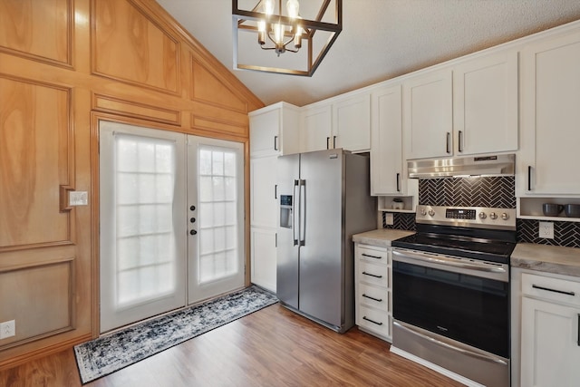 kitchen featuring appliances with stainless steel finishes, under cabinet range hood, light wood finished floors, decorative backsplash, and a notable chandelier