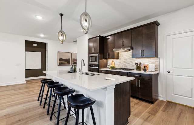 5921 Mayer Ave, Pilot Point, TX 75009 - kitchen featuring a kitchen bar, tasteful backsplash, appliances with stainless steel finishes, a sink, and light wood-style floors