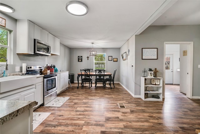 kitchen with wood finished floors, a sink, white cabinetry, and stainless steel appliances