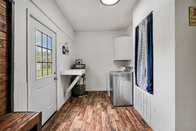 washroom with water heater, wood finished floors, washing machine and clothes dryer, baseboards, and cabinet space