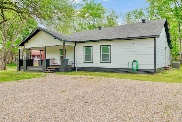 back of house featuring roof with shingles, a porch, a lawn, and central air condition unit