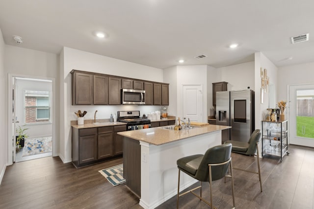 1002 Honey Maple St, Princeton, TX 75407 - kitchen featuring appliances with stainless steel finishes, a sink, dark wood finished floors, dark brown cabinets, and a center island with sink