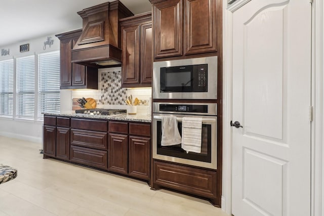 1103 Wrenwood Dr, Justin, TX 76247 - kitchen with stainless steel appliances, premium range hood, decorative backsplash, light stone countertops, and dark brown cabinets