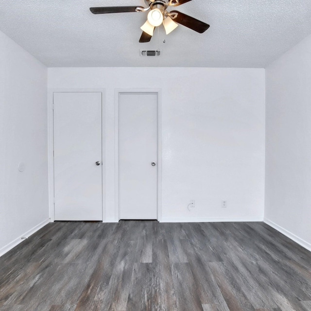 unfurnished bedroom with dark wood finished floors, a textured ceiling, baseboards, and visible vents